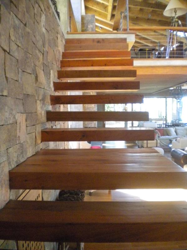 Escalera de peldaños volados de madera y muro de piedra