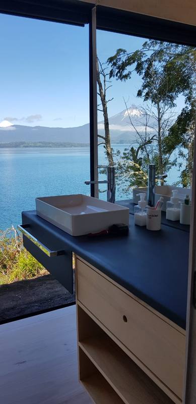Mueble de madera frente a ventanal con vista al lago y al volcán