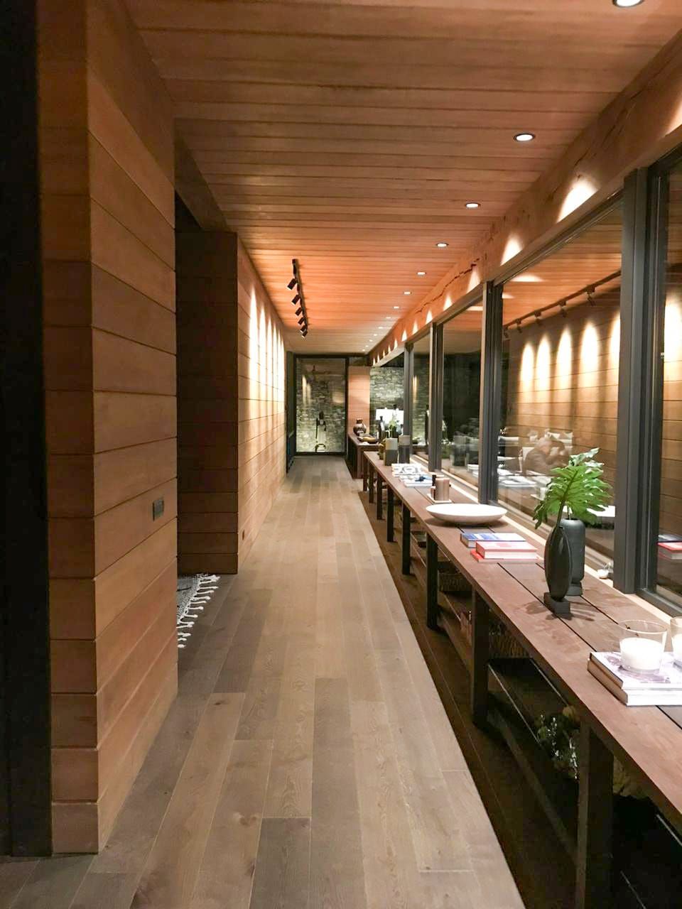 Pasillo interior revestido en madera con luz cálida, obra Lago Ranco II