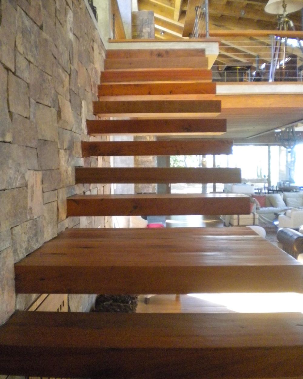 Escalera de peldaños volados de madera junto a muro de piedra, obra Lago Panguipulli