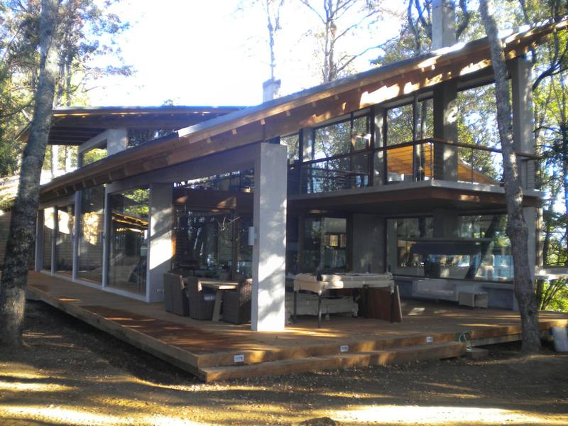 Lago Panguipulli — Casa entre árboles con terraza de madera y grandes ventanales