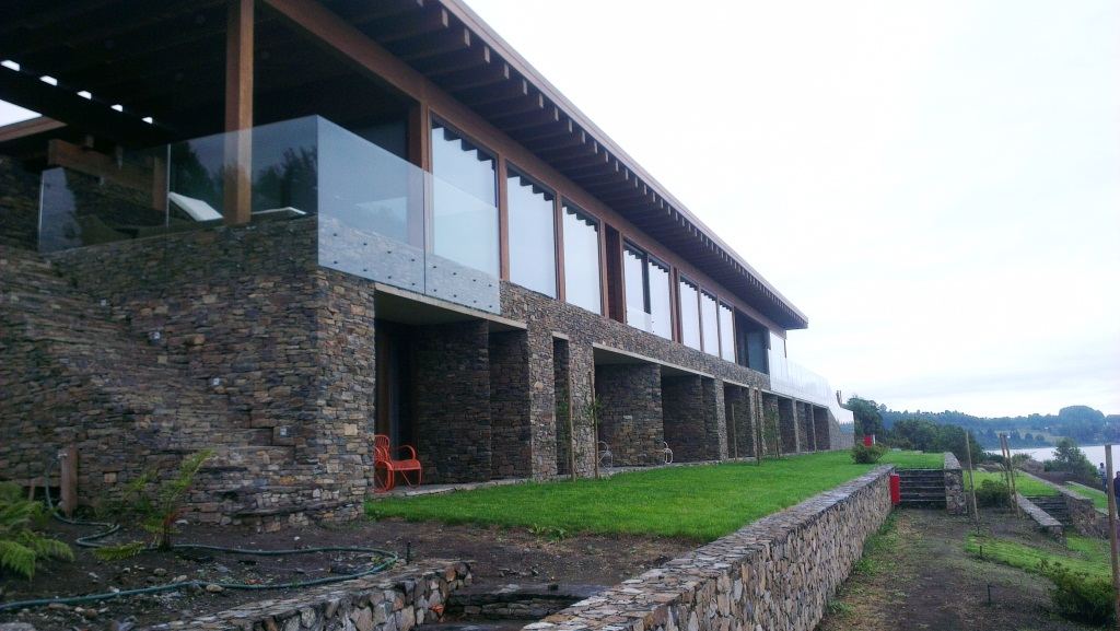 Lago Ranco I — Fachada de piedra con barandas de vidrio frente al lago