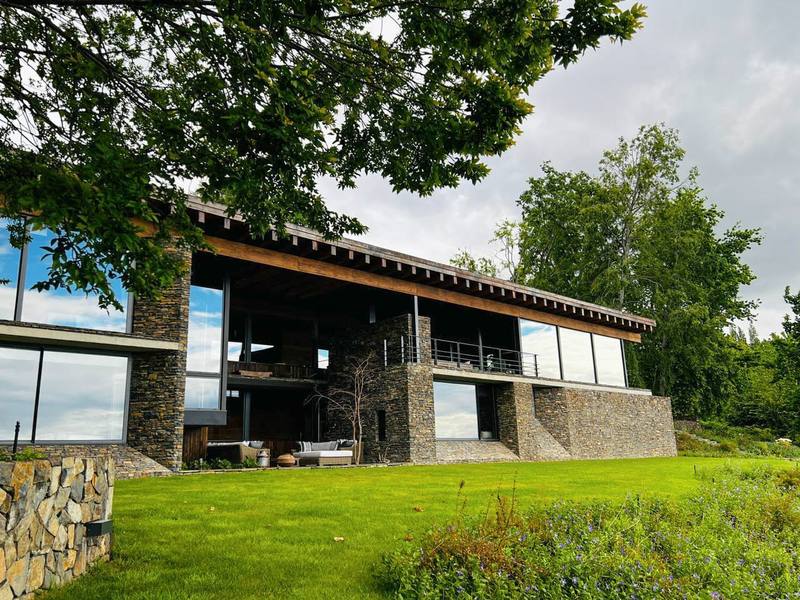Lago Ranco II — Fachada con muros de piedra y grandes ventanales